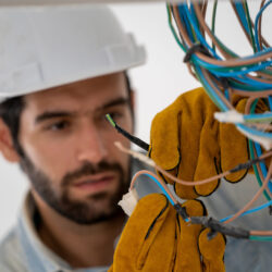 Professional electrician installing cables in wires of new house at construction site.