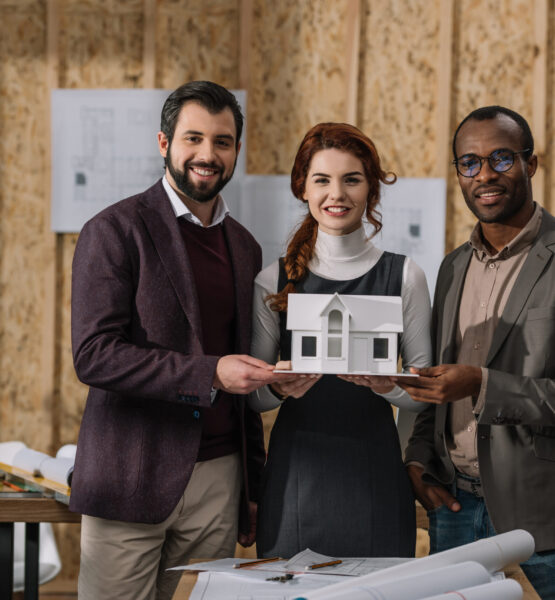 happy team of architects holding miniature model of building at office
