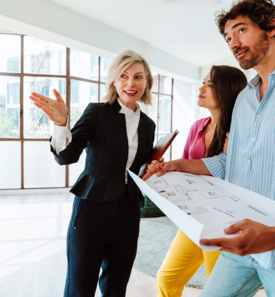 Real estate agent showing a new apartment and features of a good investment to a young couple. Woman and man buying a property in a rich area of the city.